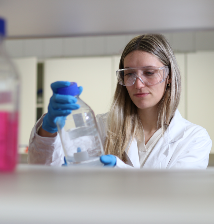 Frau im Labor mit Glasflasche